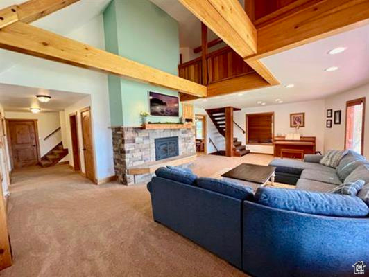Living area featuring a towering ceiling, a fireplace, stairs, carpet, and recessed lighting