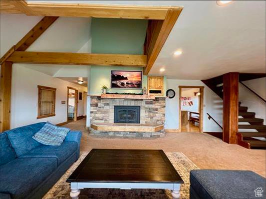 Living room featuring carpet floors, baseboards, a fireplace, and stairs
