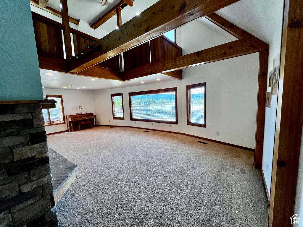 Unfurnished living room with carpet flooring, beamed ceiling, baseboards, recessed lighting, and high vaulted ceiling