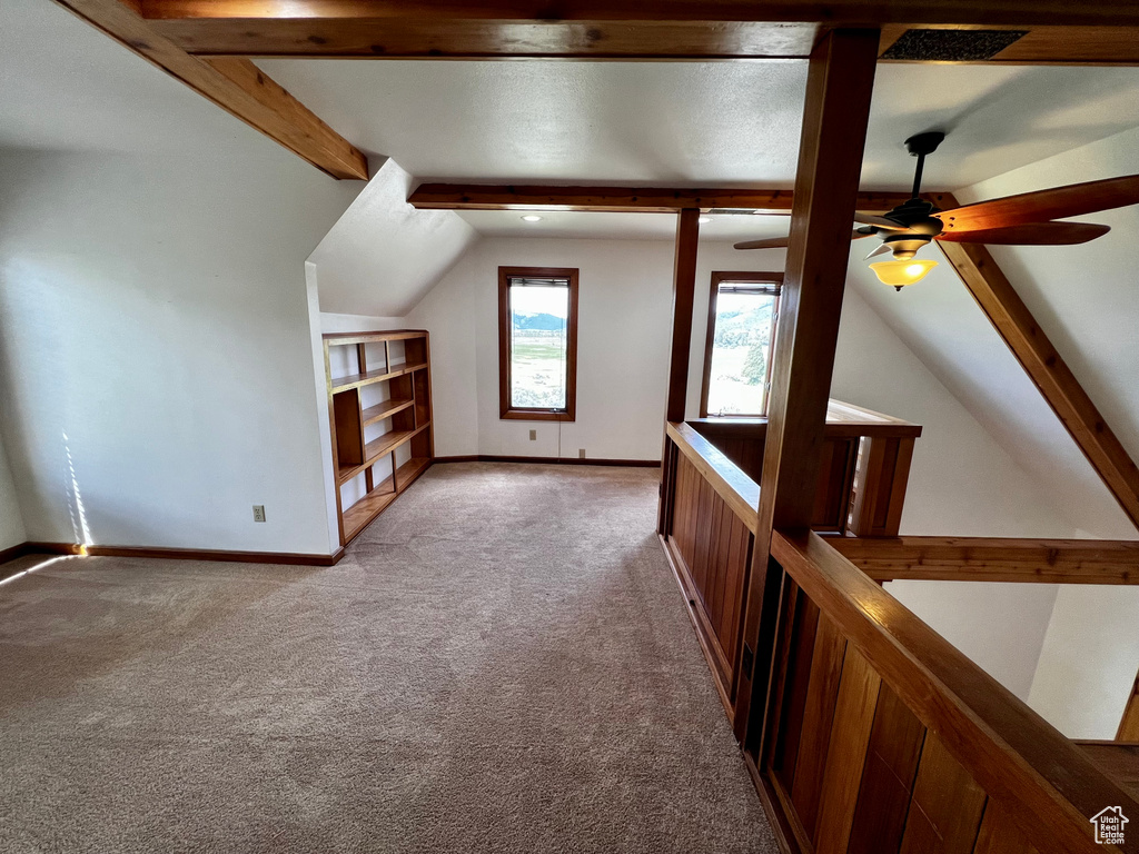 Additional living space with carpet floors, ceiling fan, baseboards, and built in shelves