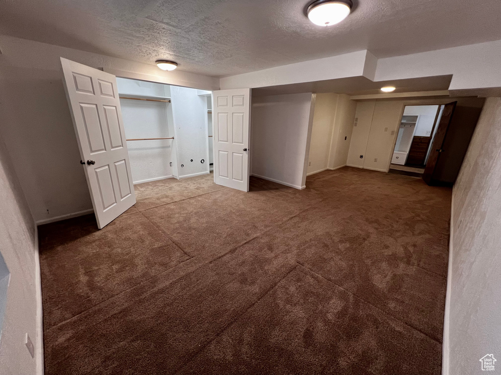 Unfurnished bedroom featuring a textured ceiling, carpet flooring, and baseboards