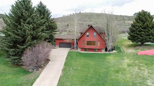 View of front facade featuring a garage, concrete driveway, and a front lawn