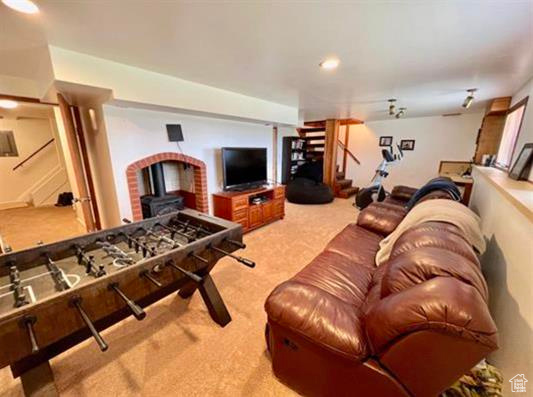Living area featuring stairs, carpet, and a wood stove