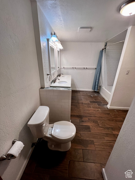 Full bathroom featuring toilet, a shower with shower curtain, wood finished floors, a textured ceiling, and vanity