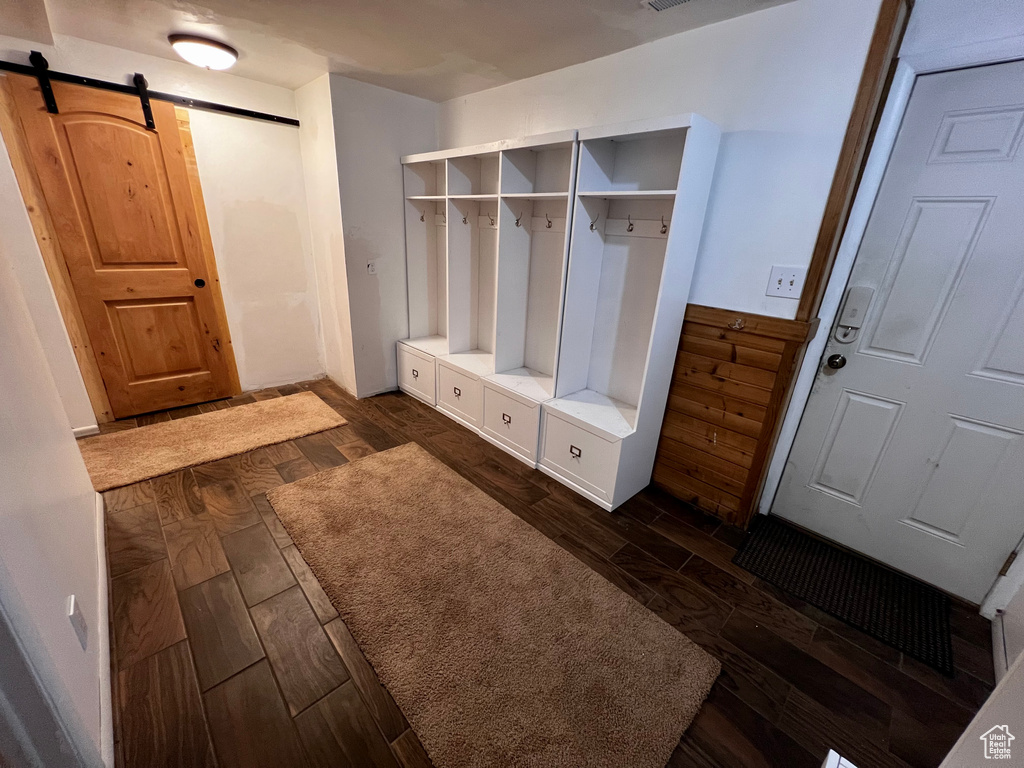 Mudroom featuring a barn door and dark wood-style floors