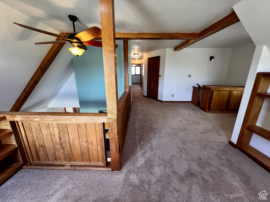 Additional living space featuring carpet, ceiling fan, beamed ceiling, a bar, and baseboards