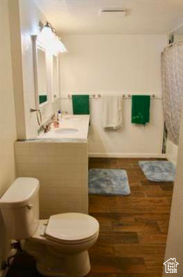 Bathroom featuring vanity, toilet, and wood finished floors