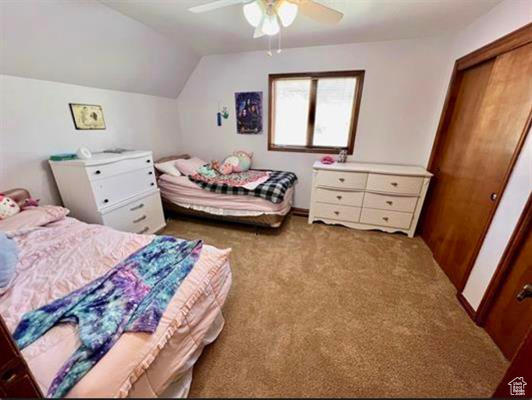Bedroom with a closet, ceiling fan, carpet, and vaulted ceiling