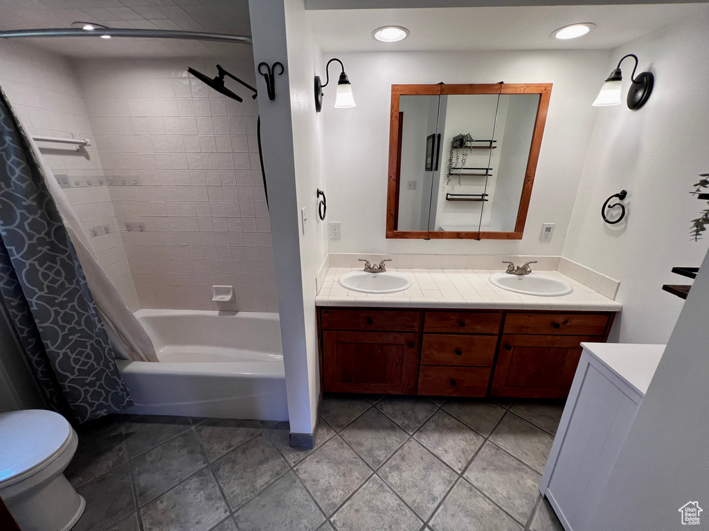 Full bathroom with double vanity, toilet, shower / bath combo, and recessed lighting