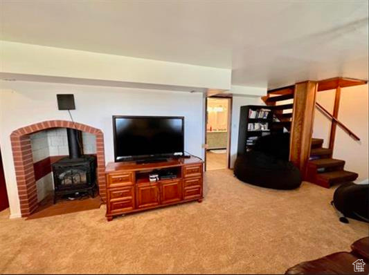 Living area with stairway, a wood stove, and light colored carpet
