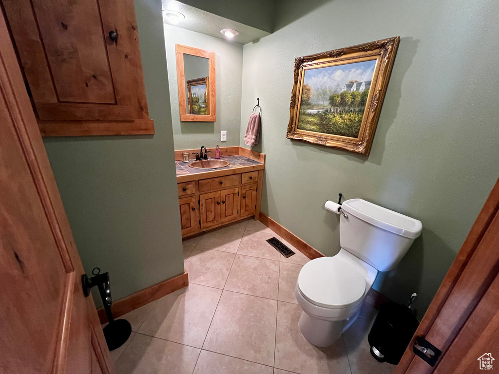 Bathroom with toilet, vanity, baseboards, and tile patterned flooring