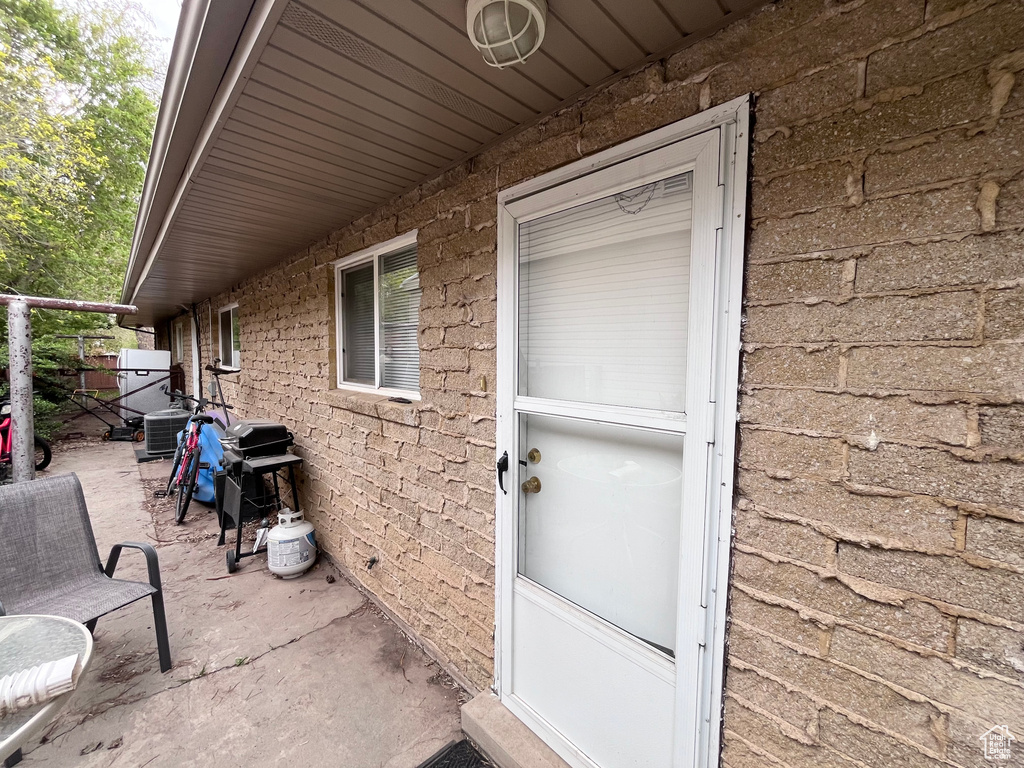 Entrance to property featuring central air condition unit and a patio area