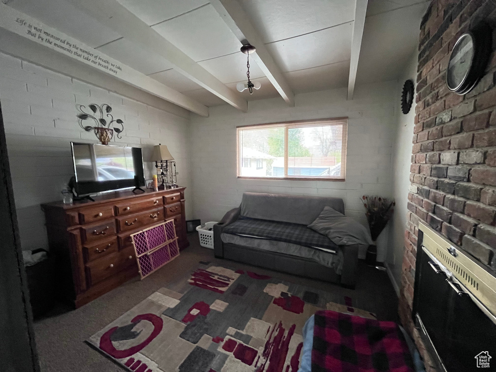 Carpeted living area with brick wall and beamed ceiling