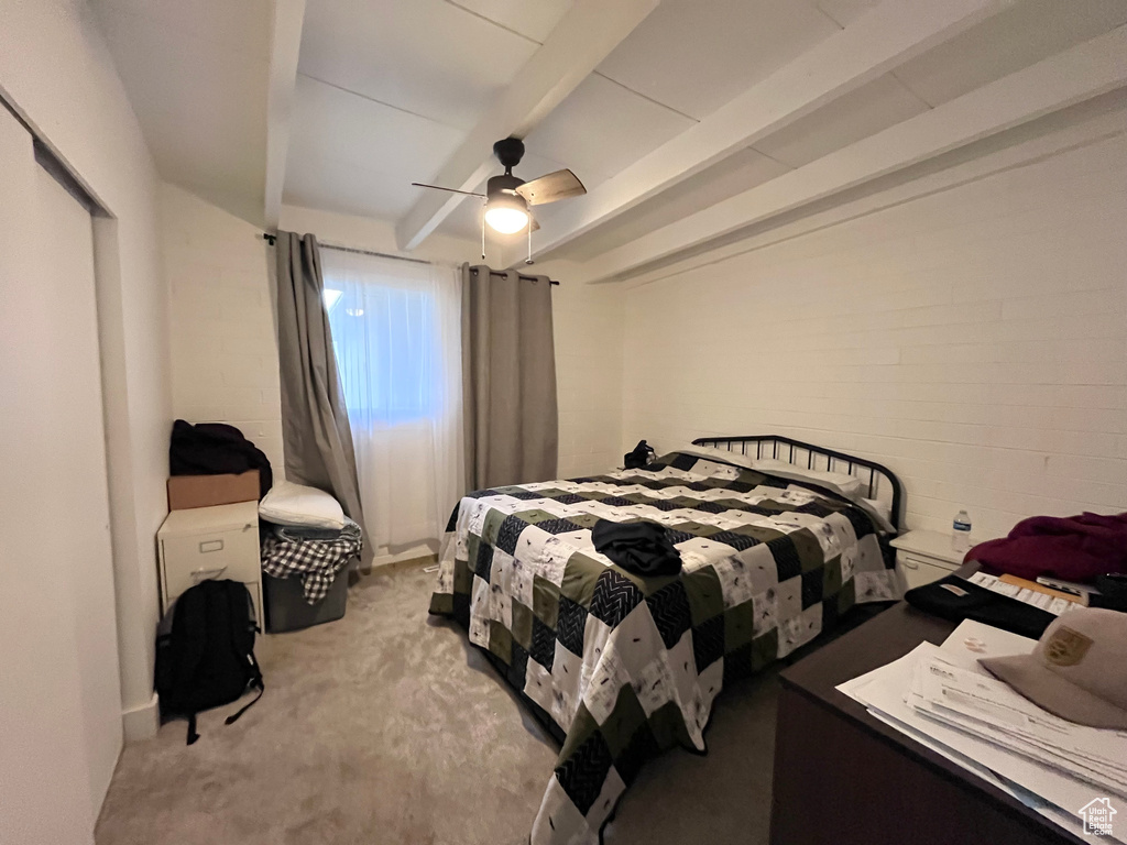 Bedroom with concrete block wall, ceiling fan, and light colored carpet