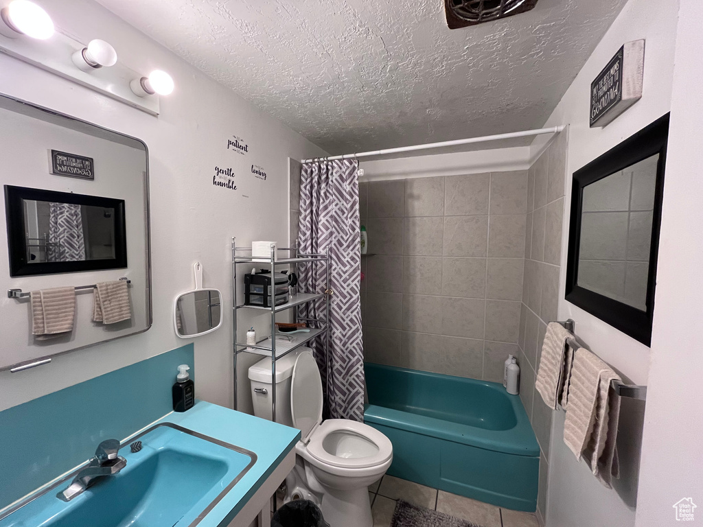 Full bathroom featuring a textured ceiling, tile patterned flooring, shower / tub combo, a sink, and toilet