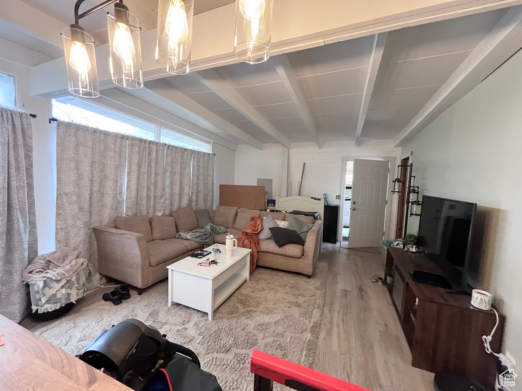 Living area with beamed ceiling, an inviting chandelier, and light wood-type flooring