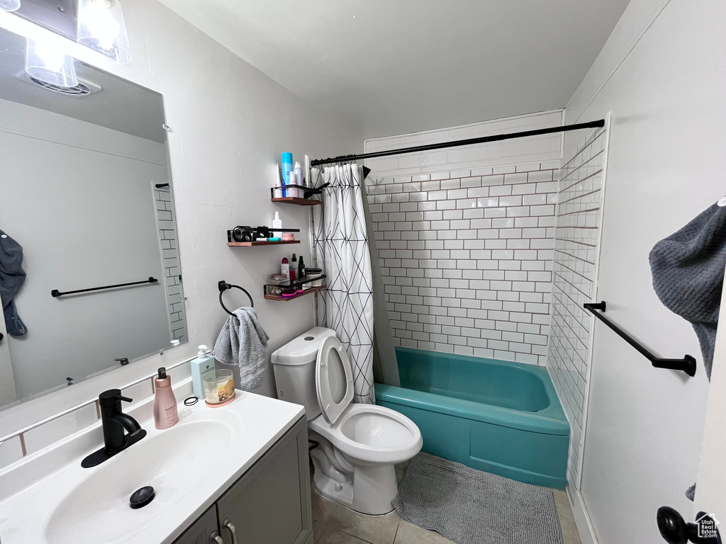 Bathroom featuring vanity, shower / tub combo with curtain, tile patterned floors, and toilet