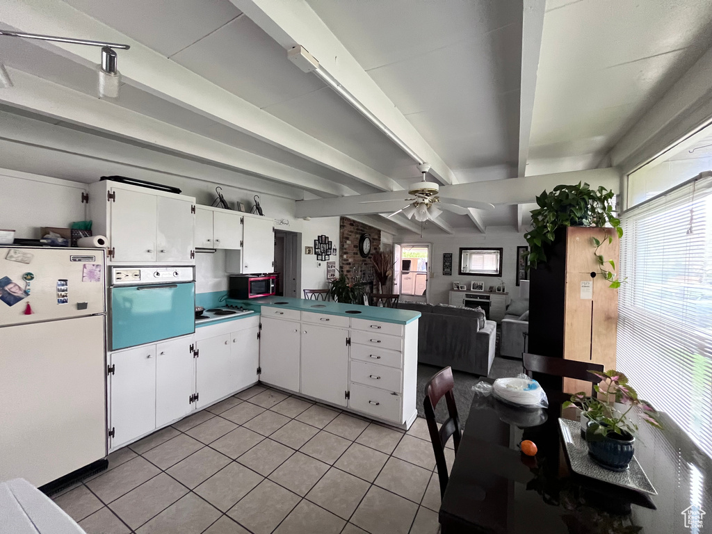 Kitchen featuring plenty of natural light, freestanding refrigerator, a peninsula, wall oven, and light tile patterned floors
