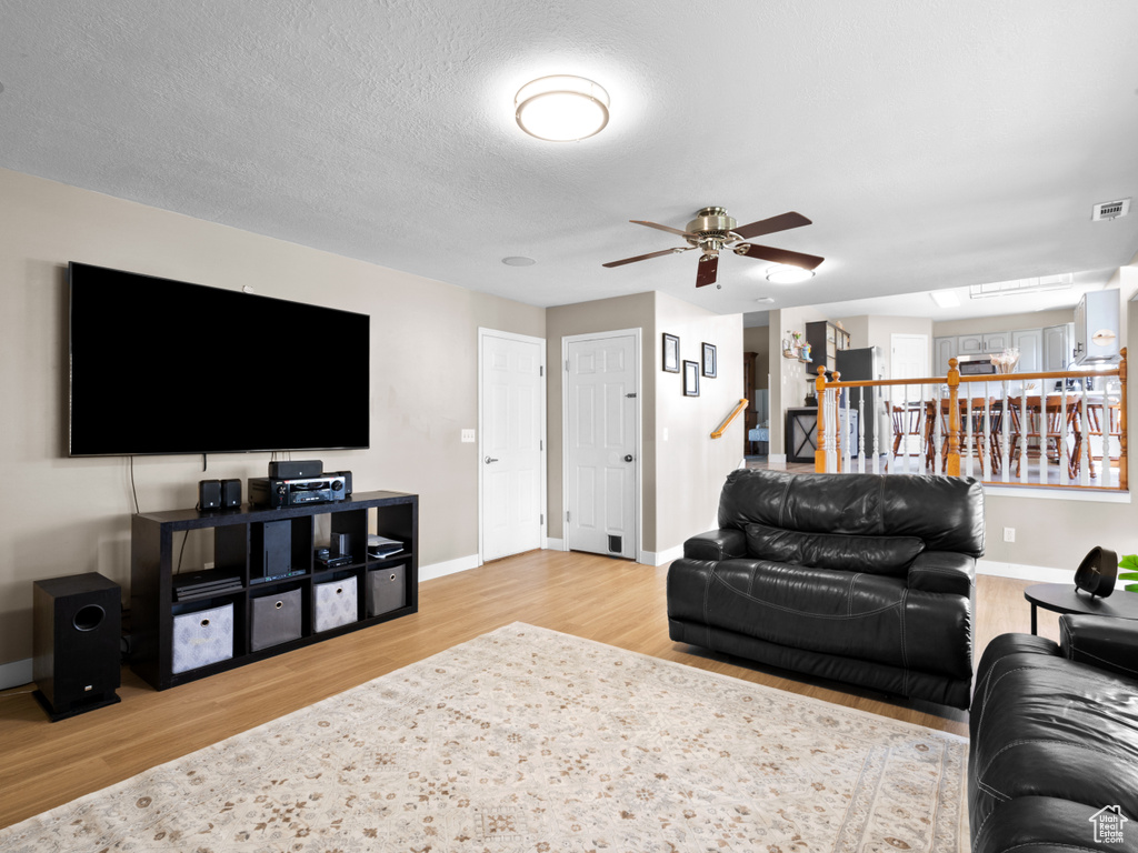Living area featuring baseboards, ceiling fan, visible vents, and wood finished floors