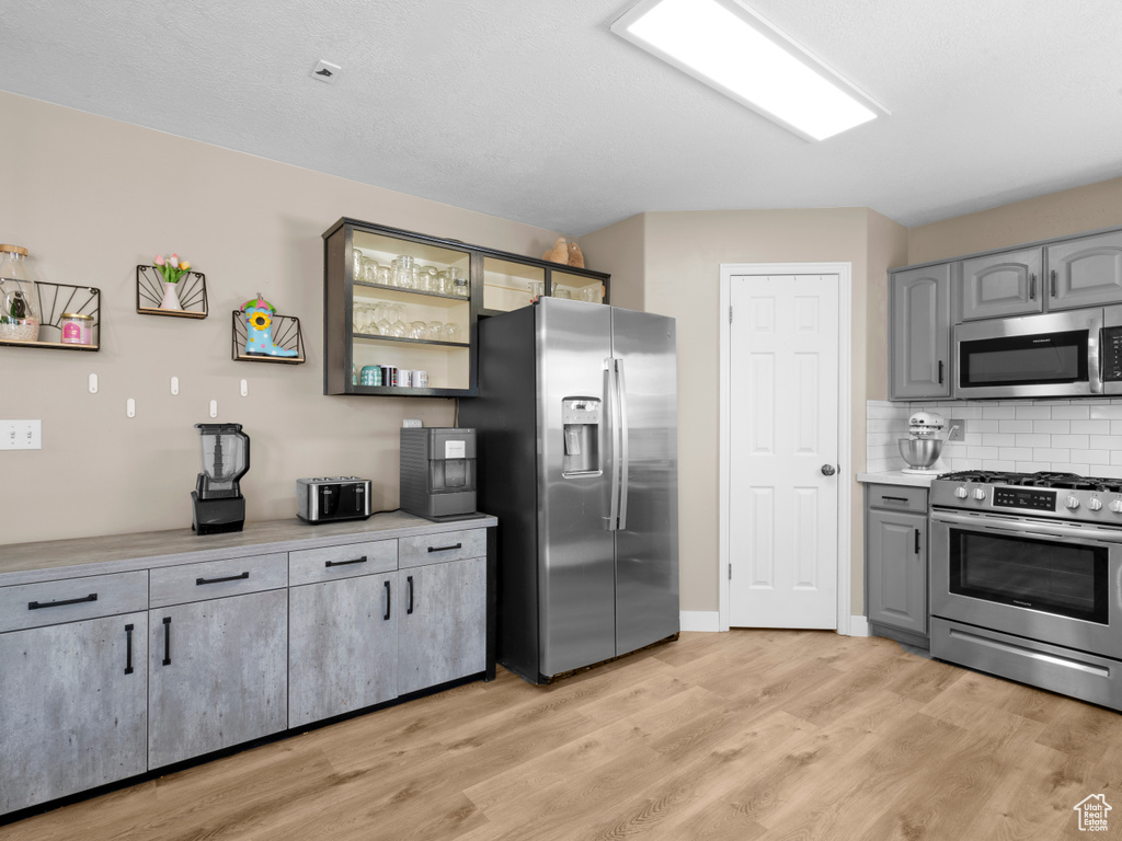Kitchen featuring light wood-style flooring, gray cabinets, appliances with stainless steel finishes, and light countertops