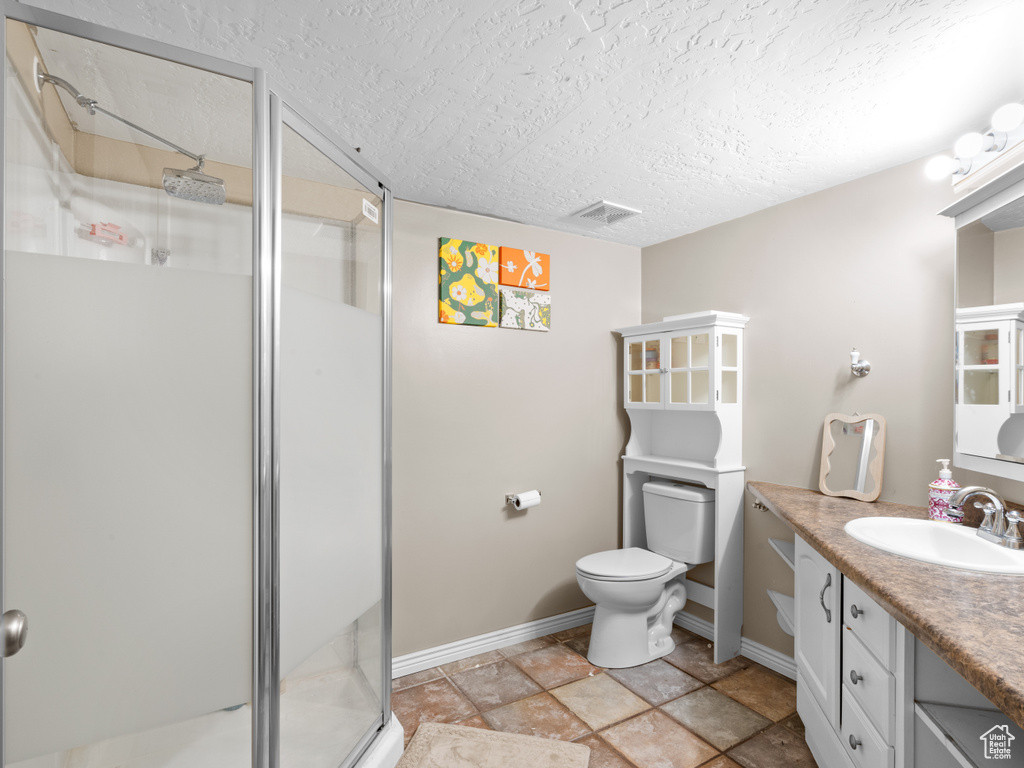 Bathroom with vanity, a stall shower, a textured ceiling, and visible vents