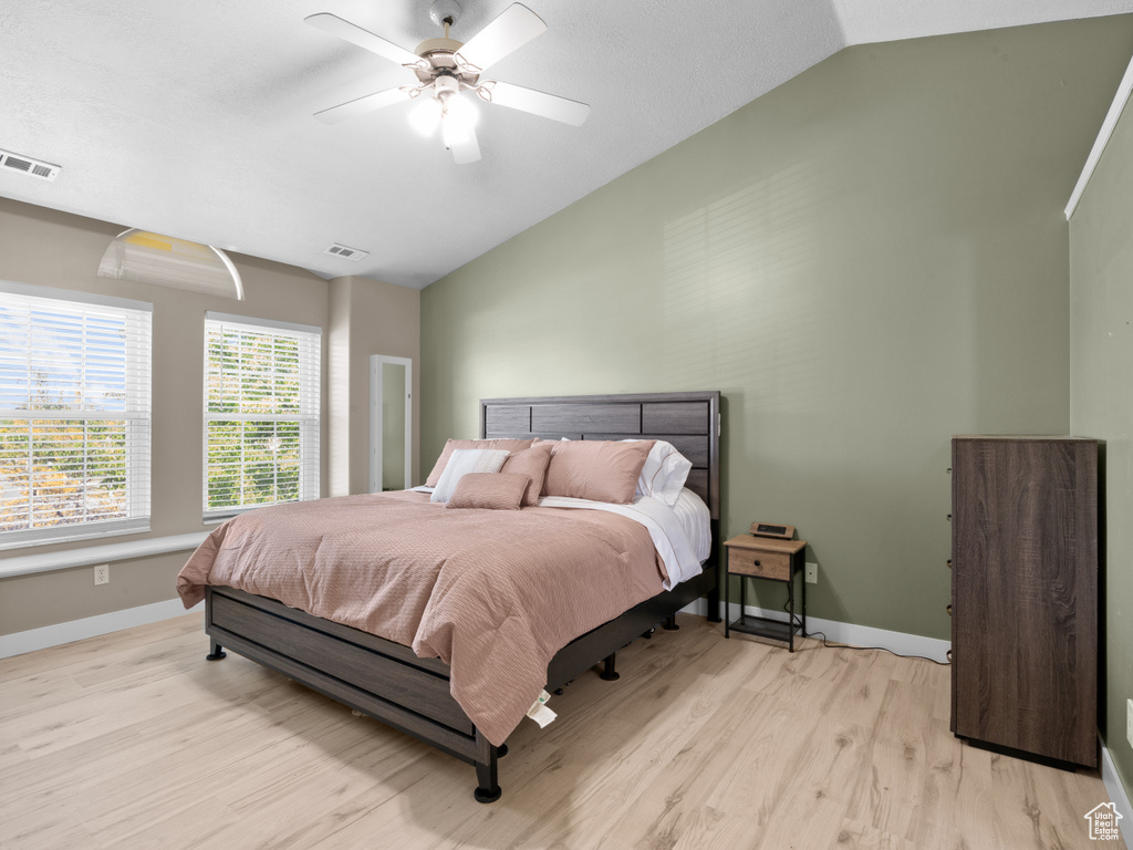 Bedroom with visible vents, baseboards, vaulted ceiling, and light wood-type flooring