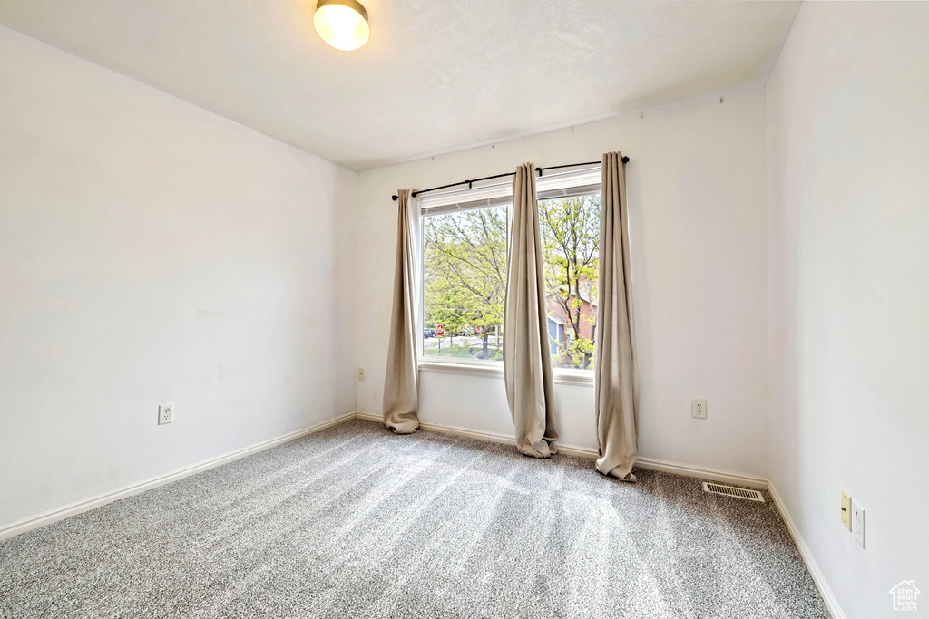 Carpeted empty room with baseboards and visible vents