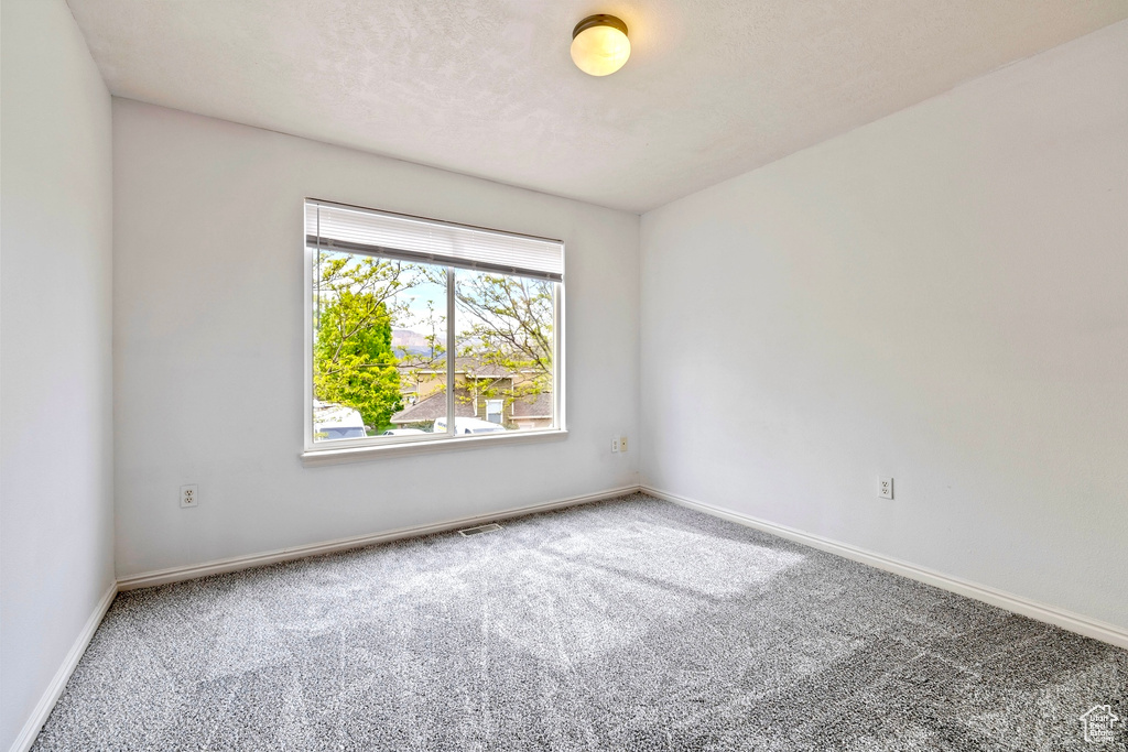 Unfurnished room with carpet floors, baseboards, and visible vents