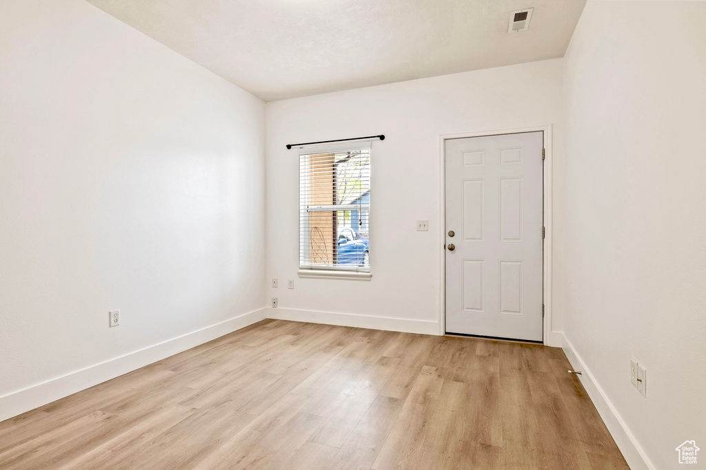 Empty room featuring baseboards, light wood-style flooring, and visible vents