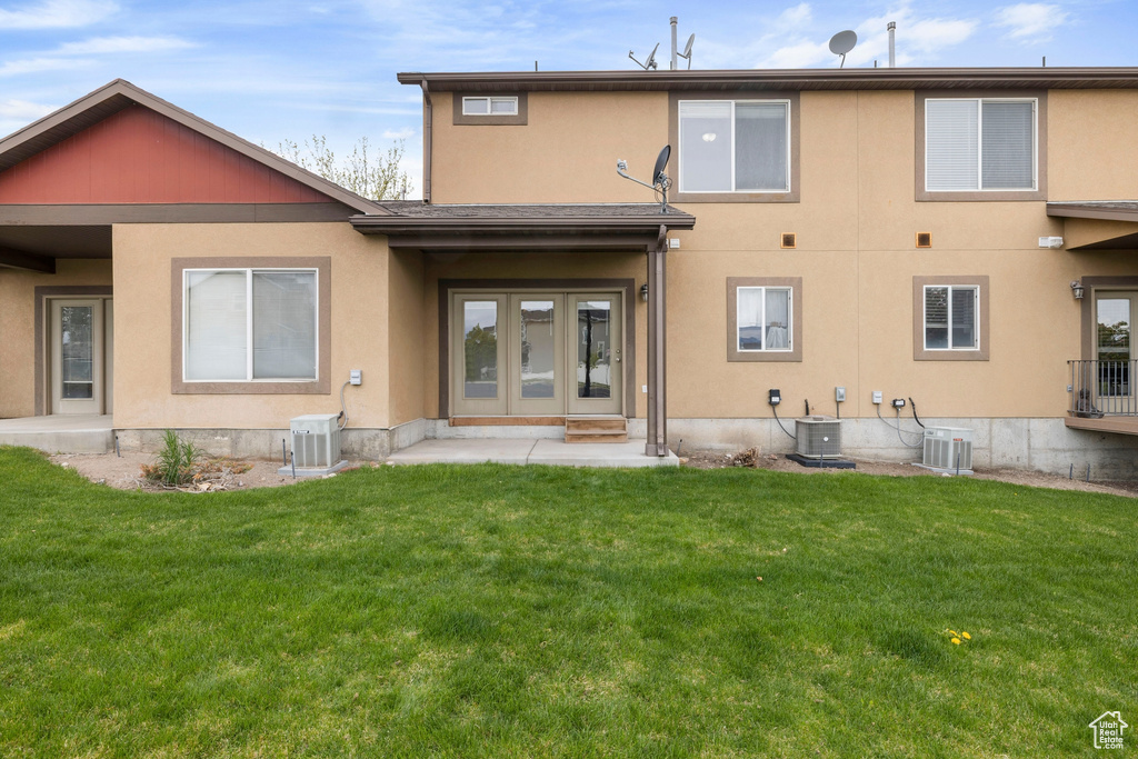 Back of house featuring stucco siding, a yard, and cooling unit