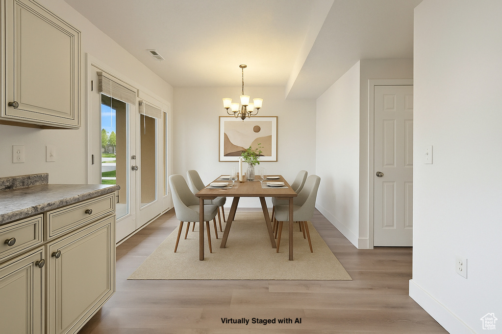 Dining area featuring light wood-type flooring, baseboards, a notable chandelier, and visible vents