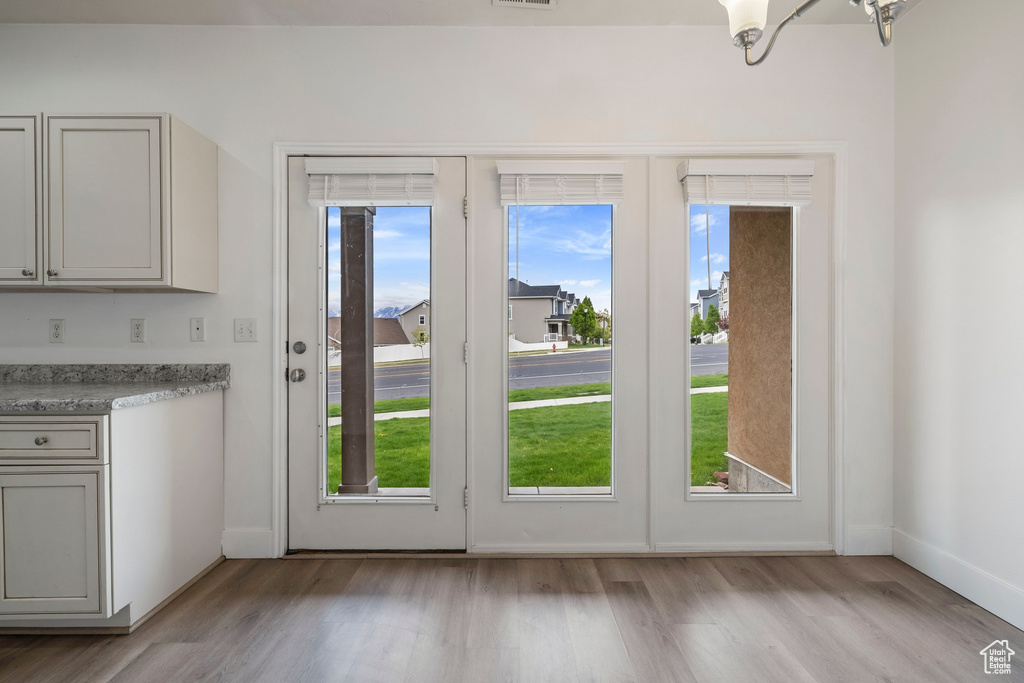 Doorway to outside with baseboards, light wood finished floors, and visible vents