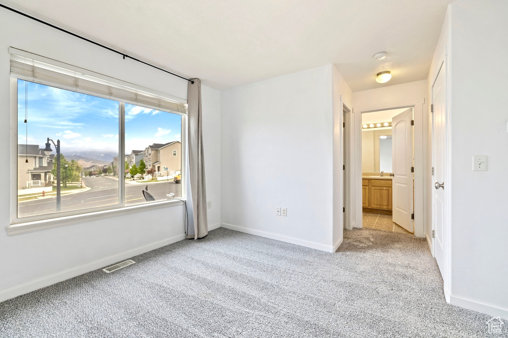 Carpeted empty room featuring visible vents, a sink, and baseboards
