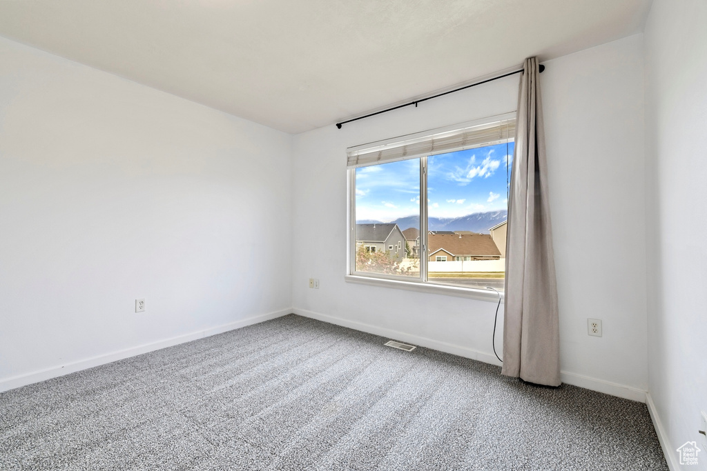Empty room with carpet floors, baseboards, and visible vents