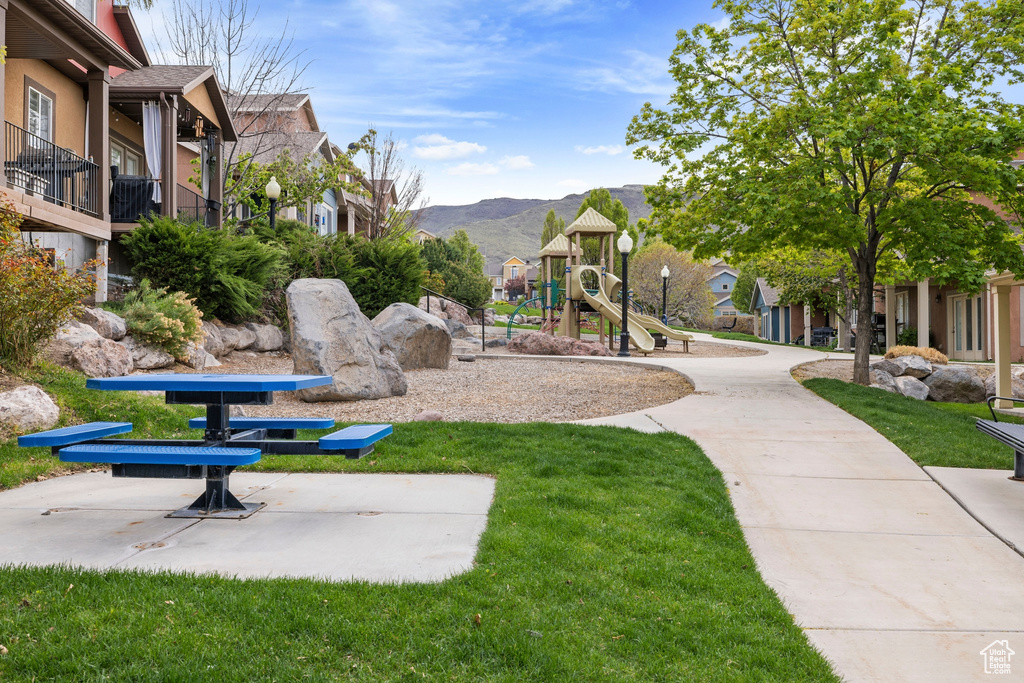 Surrounding community featuring a lawn, a mountain view, playground community, and a residential view