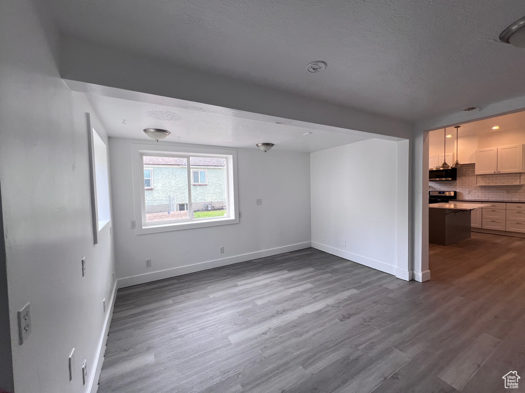 Unfurnished living room featuring baseboards, a textured ceiling, and wood finished floors