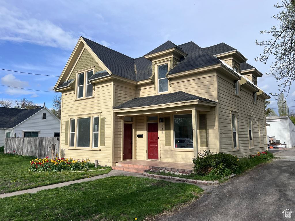 View of front facade with covered porch, fence, and a front yard