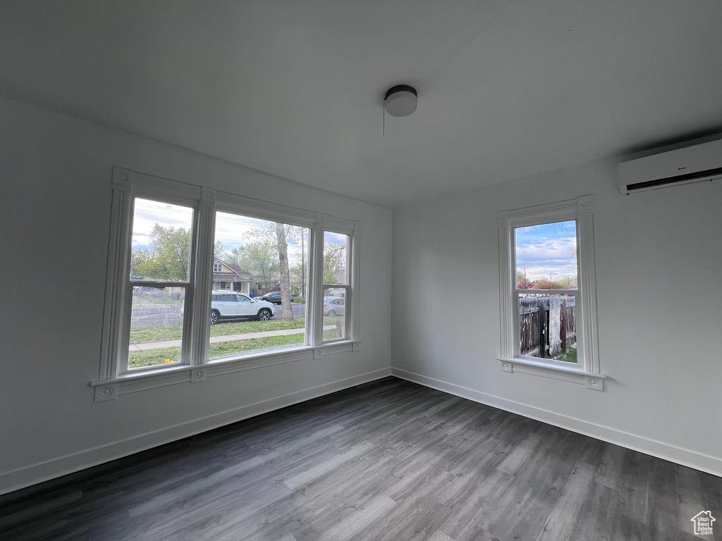 Spare room featuring plenty of natural light, an AC wall unit, and dark wood-type flooring