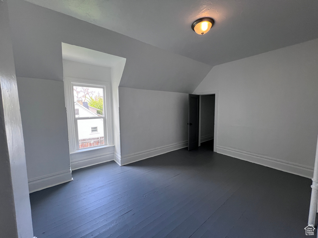 Additional living space with baseboards, vaulted ceiling, and dark wood-type flooring