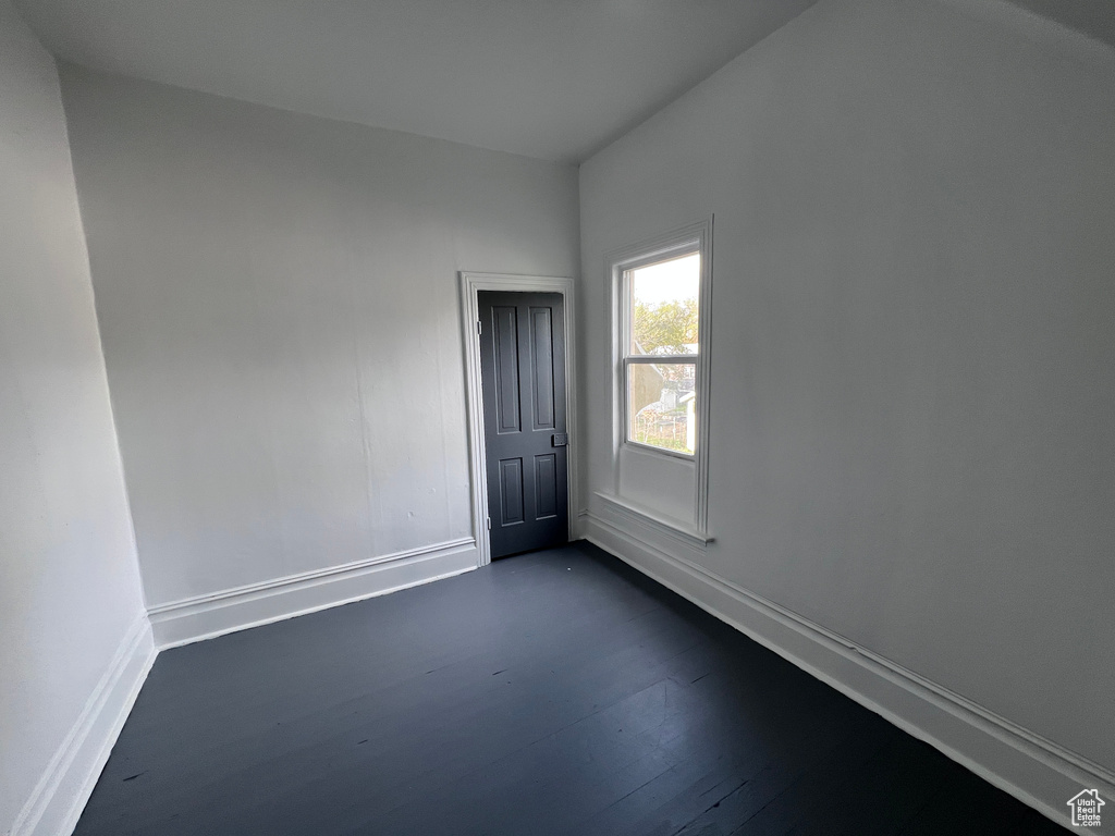 Spare room with baseboards and dark wood-type flooring