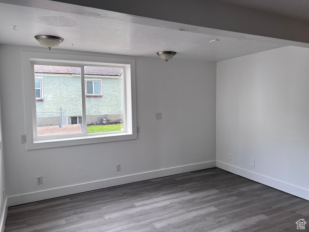 Empty room featuring baseboards, a textured ceiling, and wood finished floors