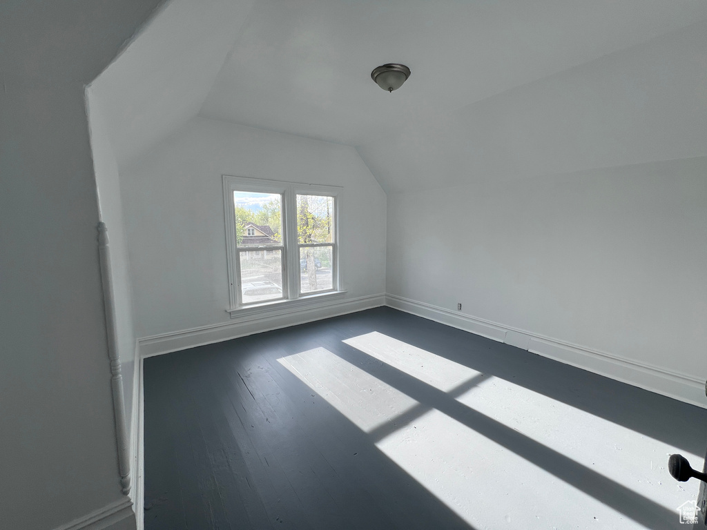Bonus room featuring baseboards, dark wood-style floors, and lofted ceiling