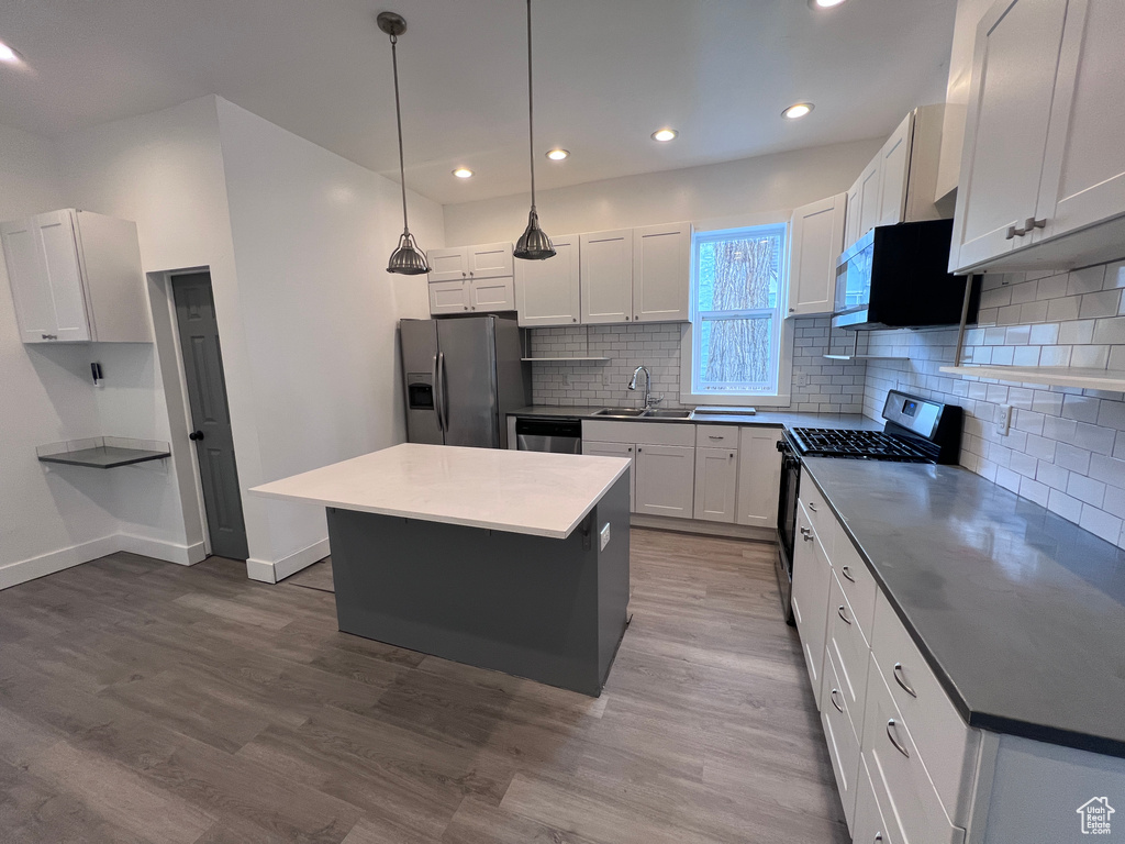 Kitchen with backsplash, stainless steel appliances, a sink, and wood finished floors