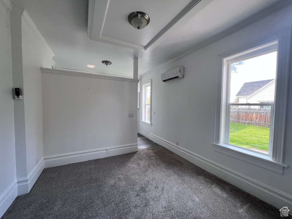 Empty room with dark carpet, ornamental molding, baseboards, and a wall mounted AC