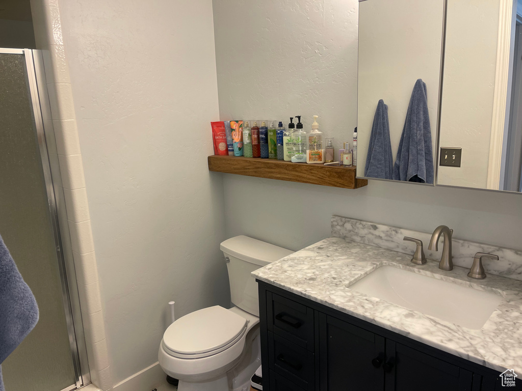 Bathroom with vanity, a textured wall, toilet, and a shower stall