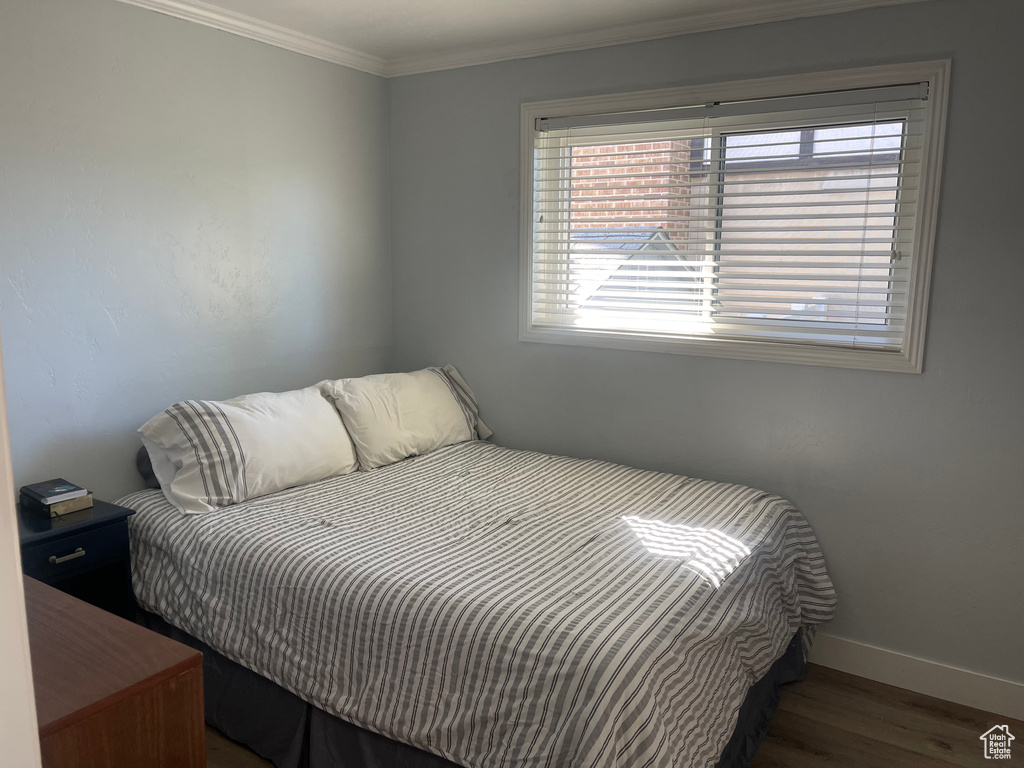 Bedroom featuring baseboards, crown molding, and wood finished floors