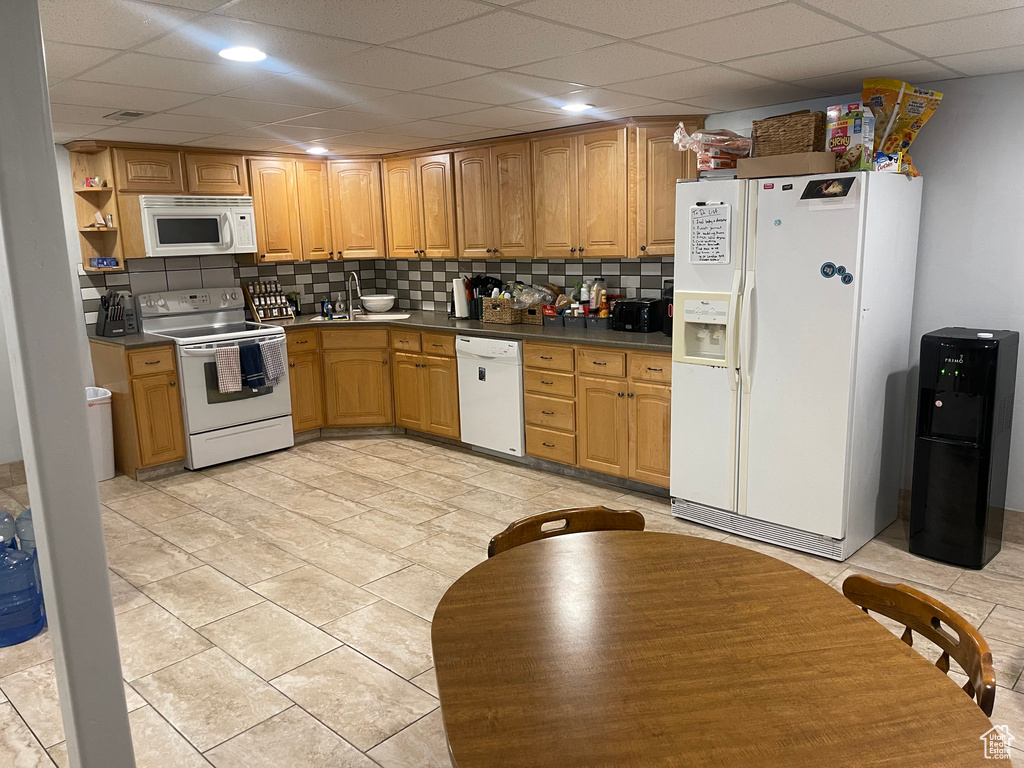 Kitchen featuring a sink, tasteful backsplash, a drop ceiling, and white appliances