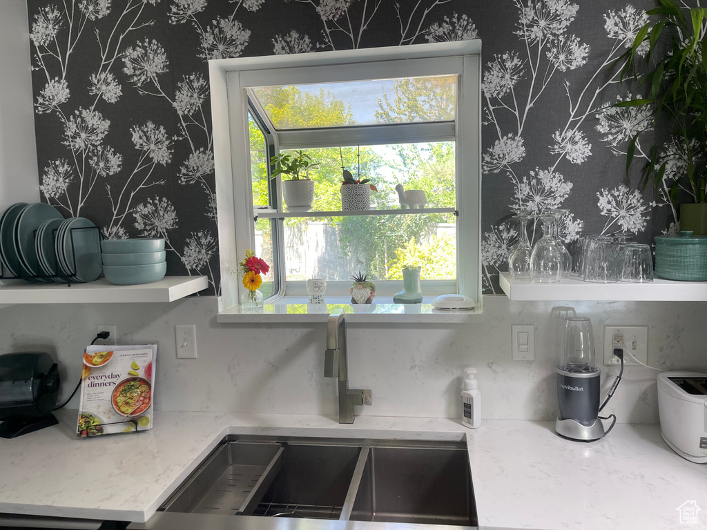 Details with wallpapered walls, light stone counters, and a sink