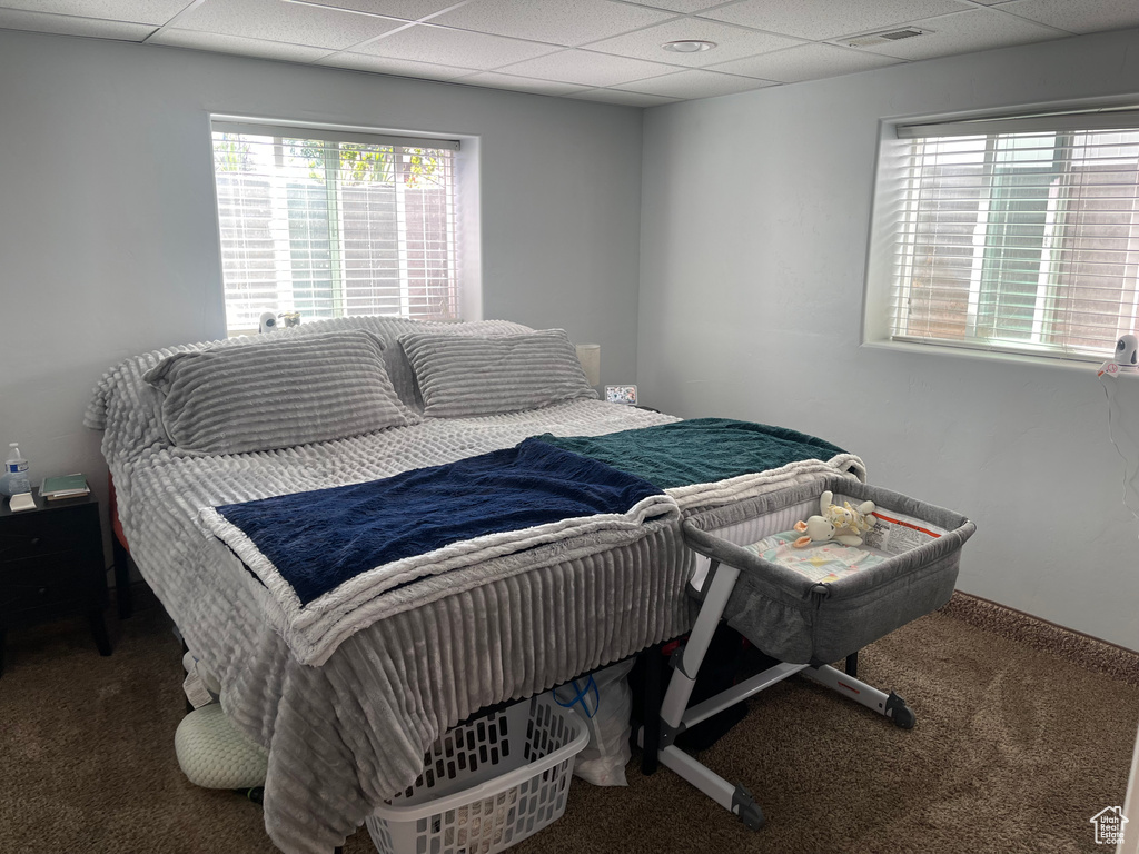 Bedroom featuring carpet flooring, visible vents, and a paneled ceiling