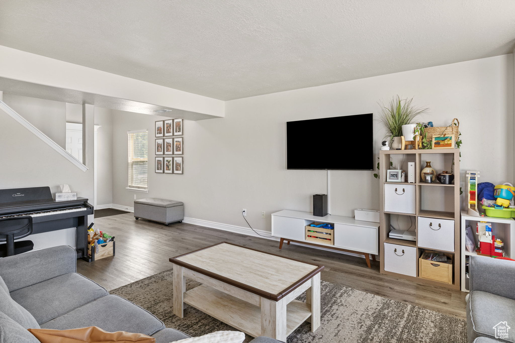 Living area featuring stairs, baseboards, and wood finished floors